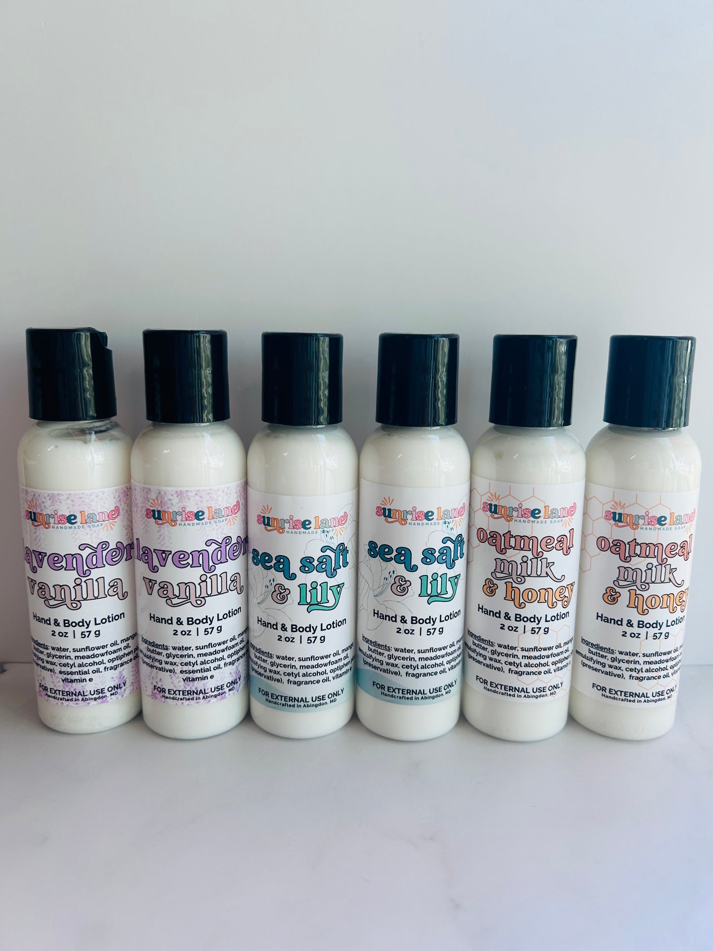 Image of 6 mini lotion bottles in three scent options: lavender vanilla, sea salt lily, and oatmeal milk honey photographed against a white background.