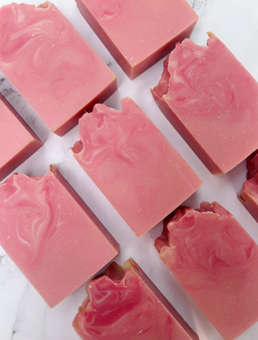 Image of 9 pink and white swirled soap bars photographed vertically on a white marble background.
